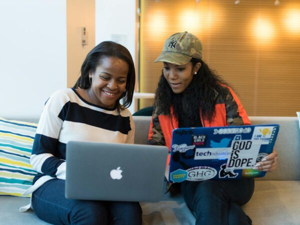 two women holding laptop