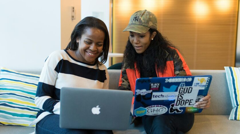 two women holding laptop