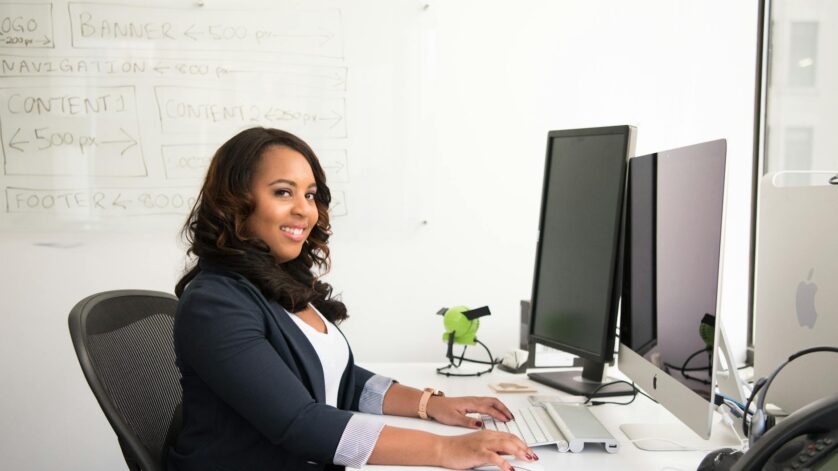 woman in professional wear seated in front of monitor