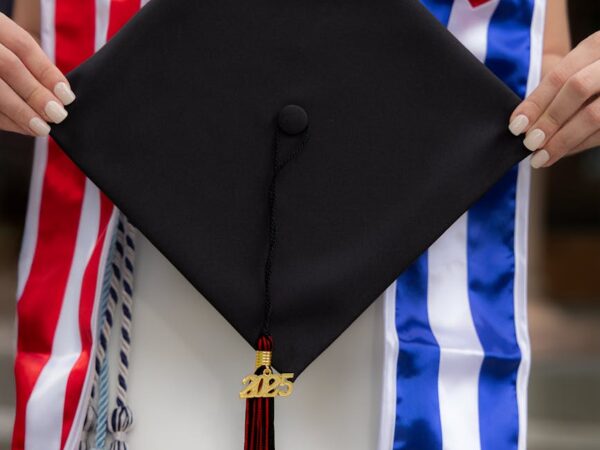 graduate holding cap with cuban and american flags