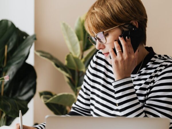 busy woman speaking on smartphone and writing notes