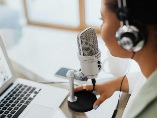 woman with headset speaking over a condenser microphone