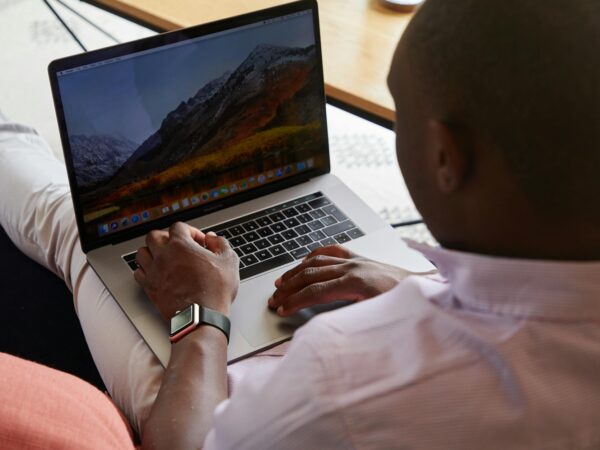 black man with smart watch using touchpad of laptop