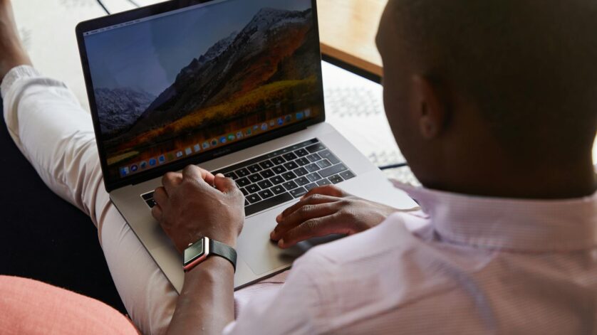 black man with smart watch using touchpad of laptop