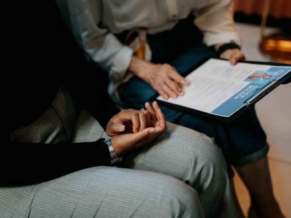 person in white long sleeve shirt holding a clipboard with resume