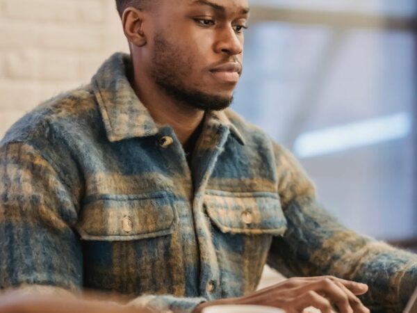 serious black man working on laptop at wooden table