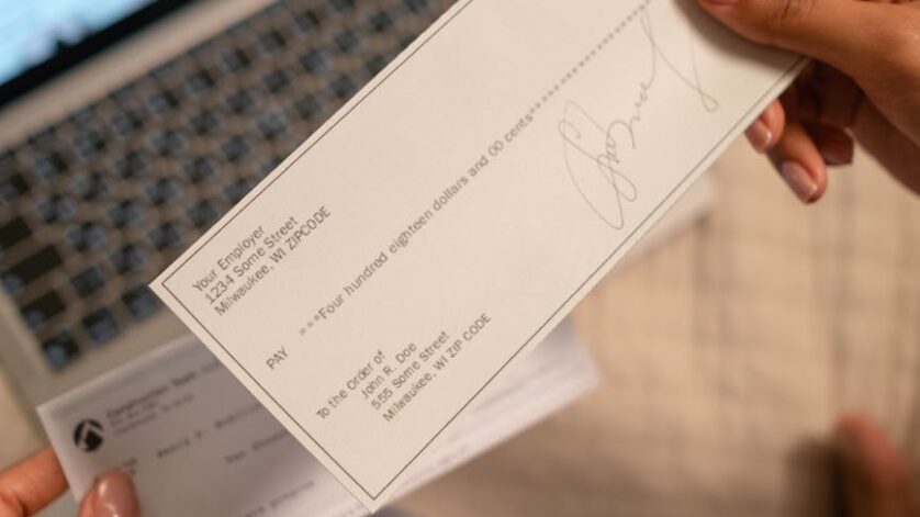 a person s hand holding a cheque