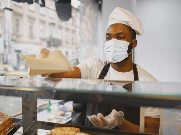 man standing behind a counter wearing face mask