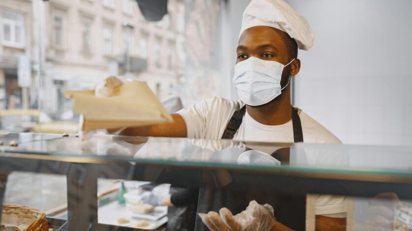 man standing behind a counter wearing face mask