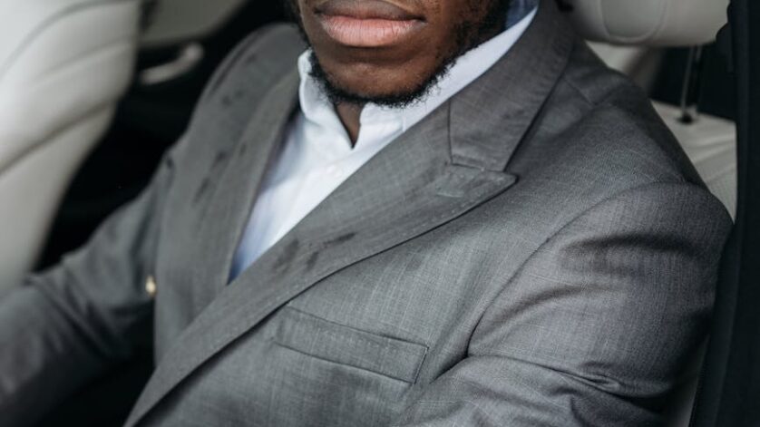 man in gray suit jacket sitting inside the car