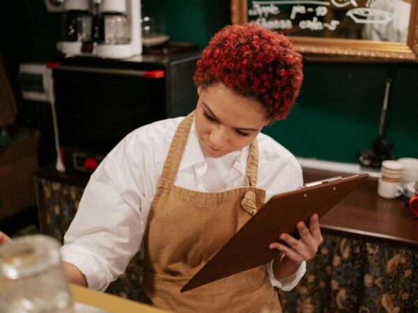 woman wearing brown apron holding brown clipboard