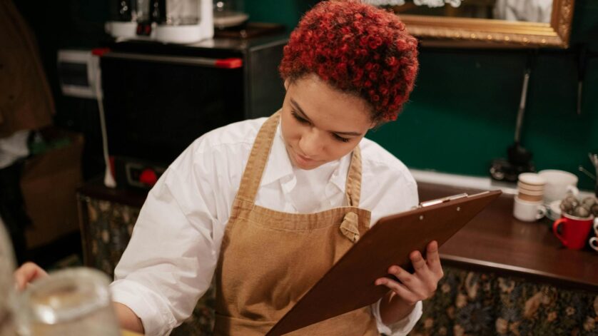 woman wearing brown apron holding brown clipboard