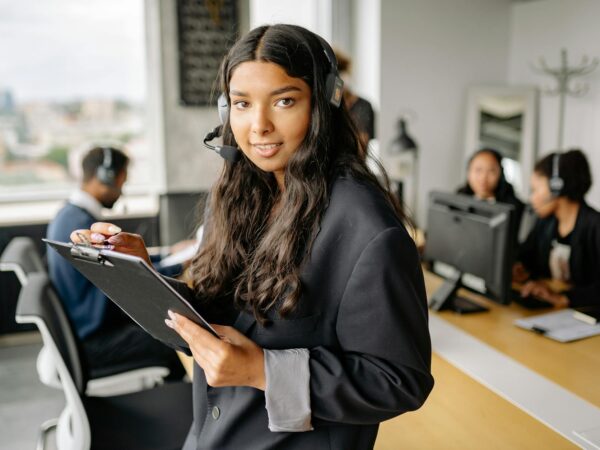 woman in black blazer holding a black clipboard and a pen