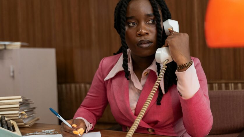 woman in a pink blazer talking on a telephone