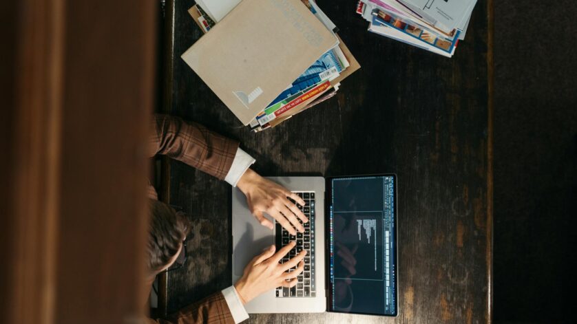 a man in a brown blazer typing on his laptop