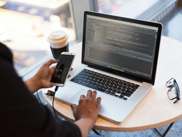 person holding smartphone while using laptop