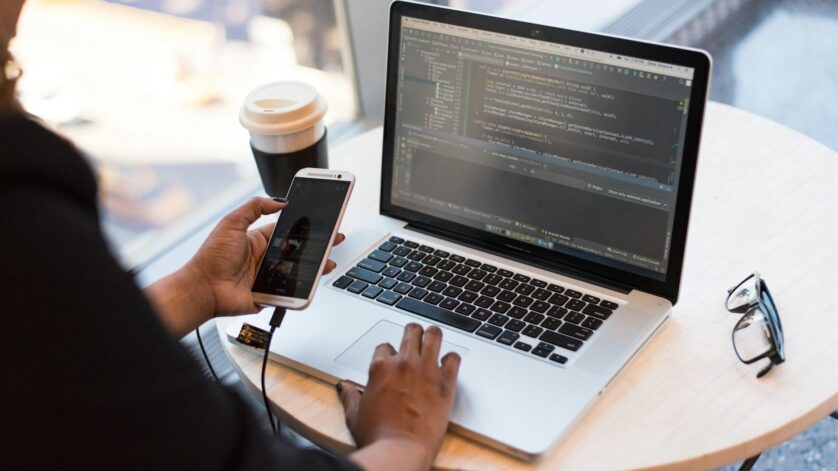 person holding smartphone while using laptop