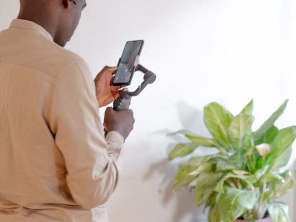 a man is holding a cell phone in front of a plant