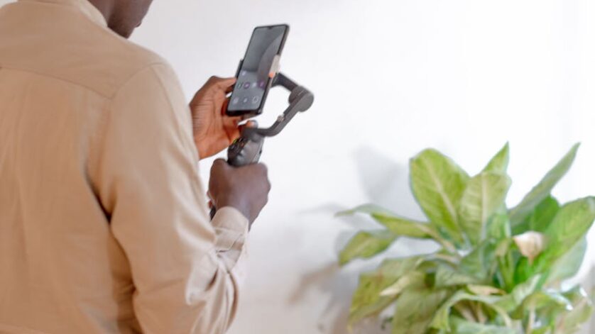 a man is holding a cell phone in front of a plant