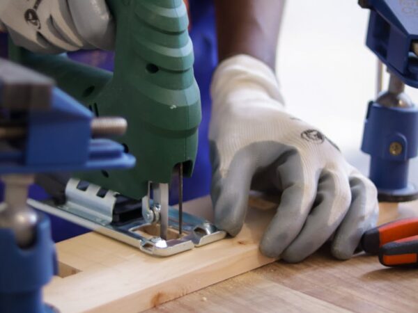 carpenter using jigsaw power tool to cut wood
