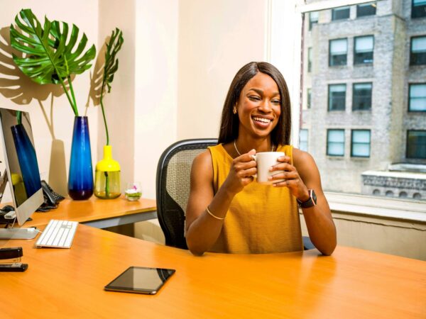 woman holding white ceramic mug at desk