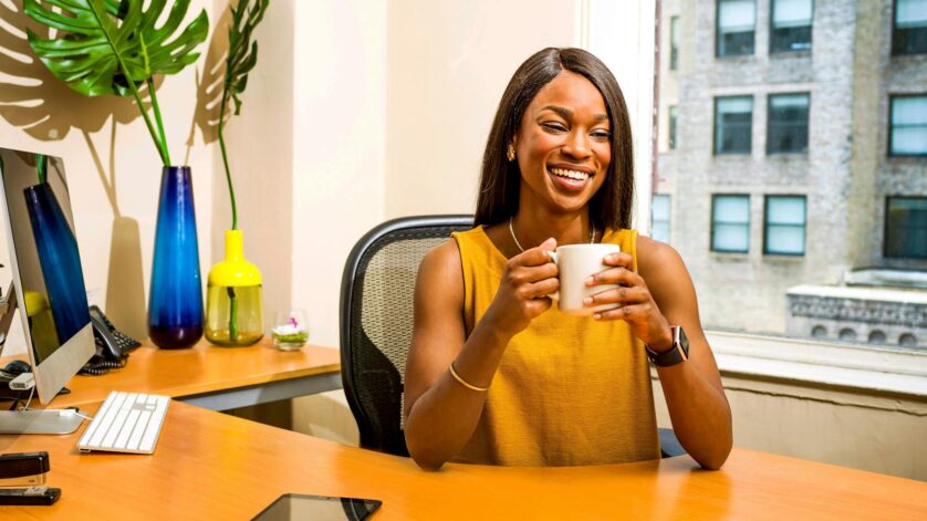 woman holding white ceramic mug at desk