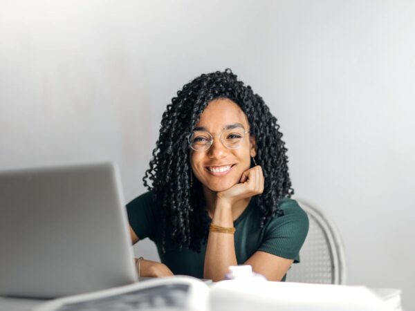 happy ethnic woman sitting at table with laptop