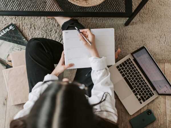 faceless lady with notebook and laptop on floor at home