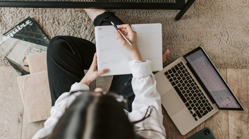 faceless lady with notebook and laptop on floor at home