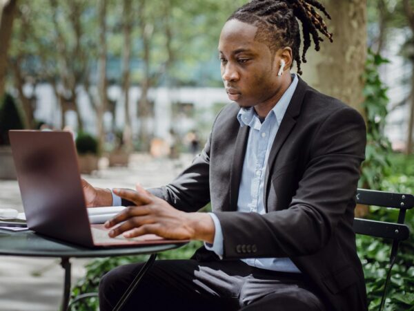 focused black businessman analyzing data on laptop in street cafe