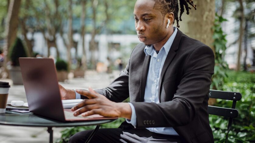 focused black businessman analyzing data on laptop in street cafe