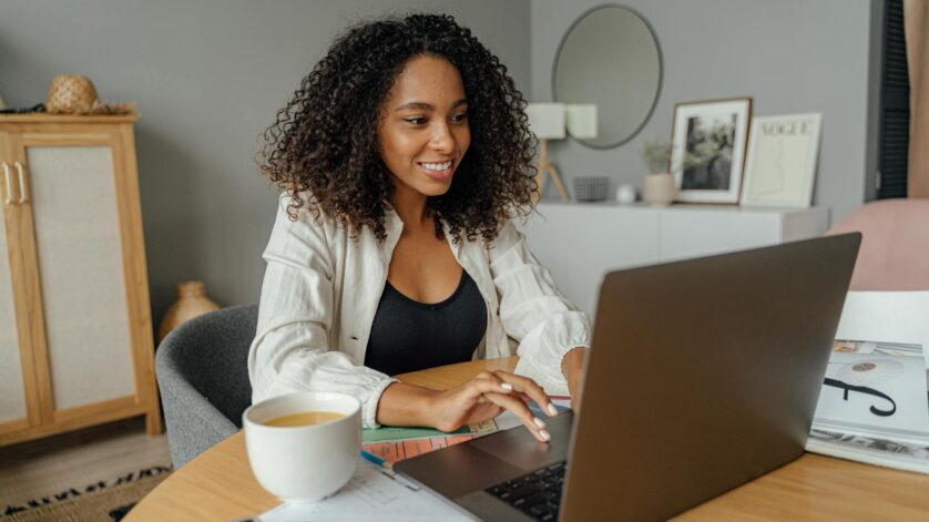 woman in white blazer using macbook pro on brown wooden table