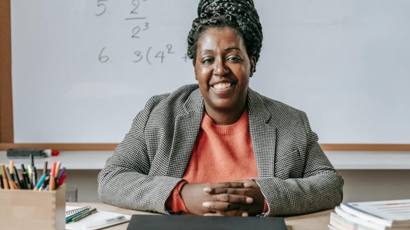 black cheerful woman smiling and sitting at table