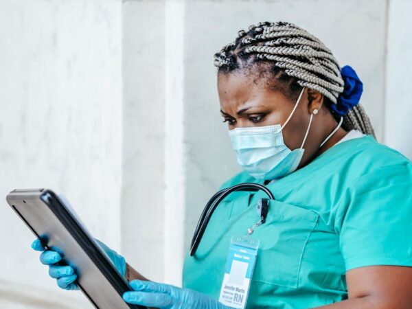 black physician in uniform with clipboard at work
