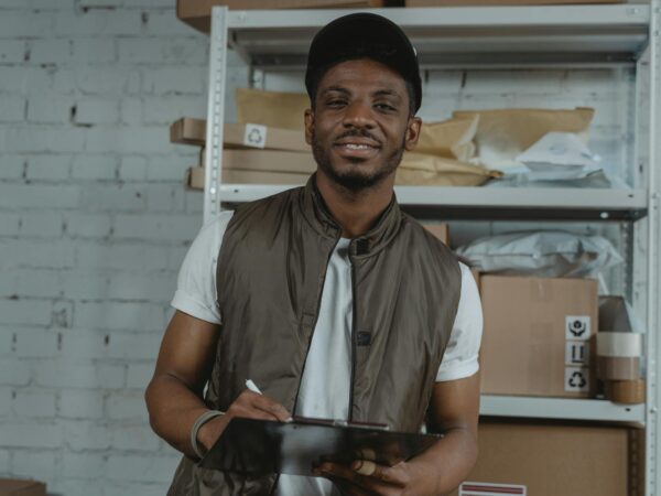 man in white button up shirt and black cap holding a clipboard