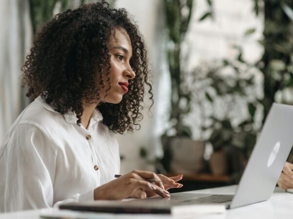 photograph of a woman with curly hair working on her laptop