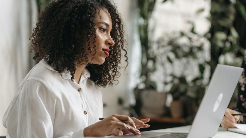 photograph of a woman with curly hair working on her laptop