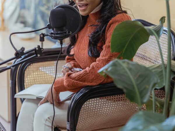 stylish young ethnic lady recording podcast in light studio