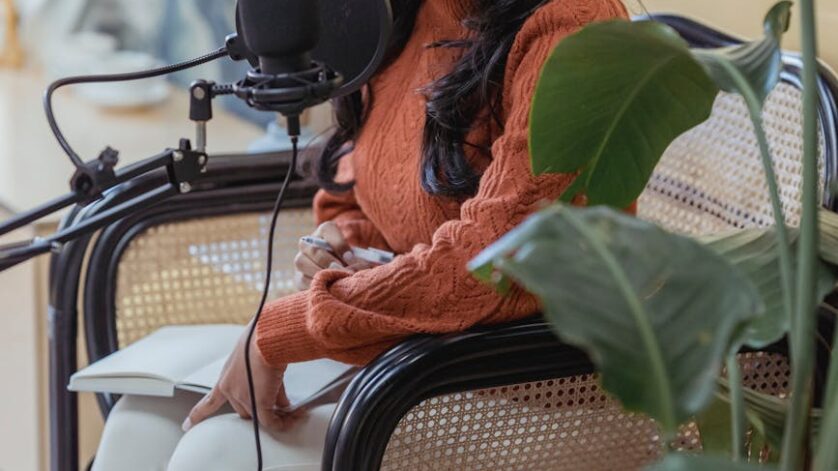 stylish young ethnic lady recording podcast in light studio